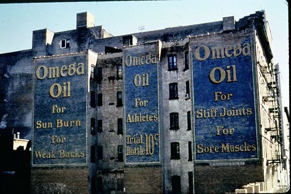 Four storey blue and yellow hand painted sign on a New York wall advertising Omega Oil