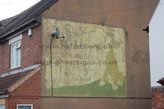 Faded hand painted sign on a building with a cow illustration advertising Bovril