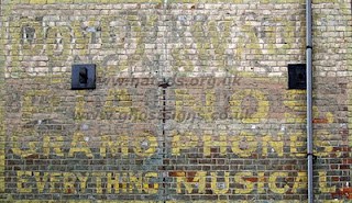 Hand painted sign on building advertising a musical shop.