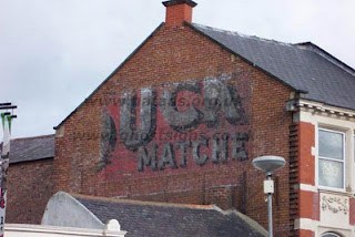 Partial remains of a hand painted sign on a building advertising Puck Matches