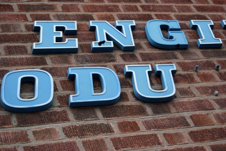 Section of blue raised lettering mounted onto brickwork