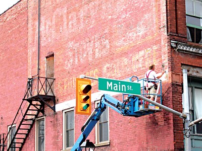 Signpainters as work on the restoration of a ghostsign in Cambridge Ontario