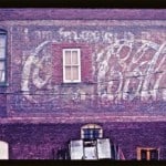 Hand painted sign on a wall advertising coca-cola