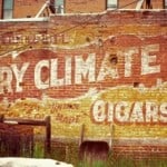 Hand painted sign on a wall advertising Dry Climate Cigars