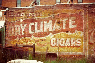 Hand painted sign on a wall advertising Dry Climate Cigars