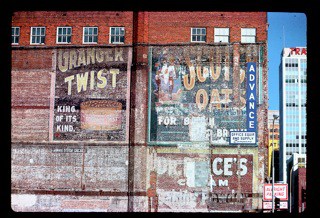 Hand painted signs on a wall, one advertising Scotch Oats