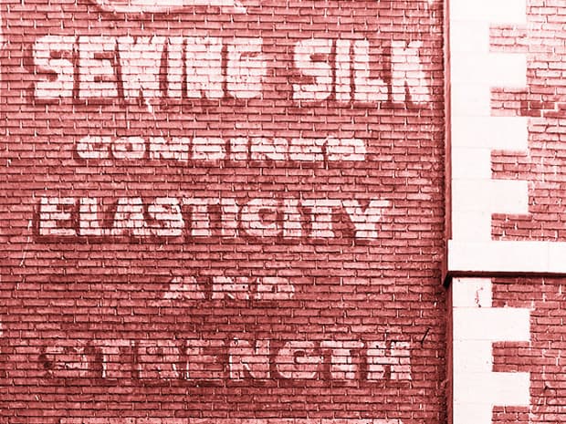 Fading hand-painted sign for Sewing Silk on Montreal wall