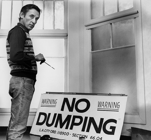 Photo of Ed Ruscha painting a 'No Dumping' sign