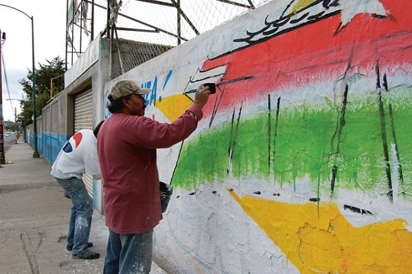 Signwriters painting a wall advertising a music event in Mexico