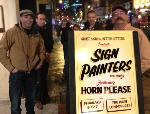 Four sign painters and a sign advertising the Sign Painters film