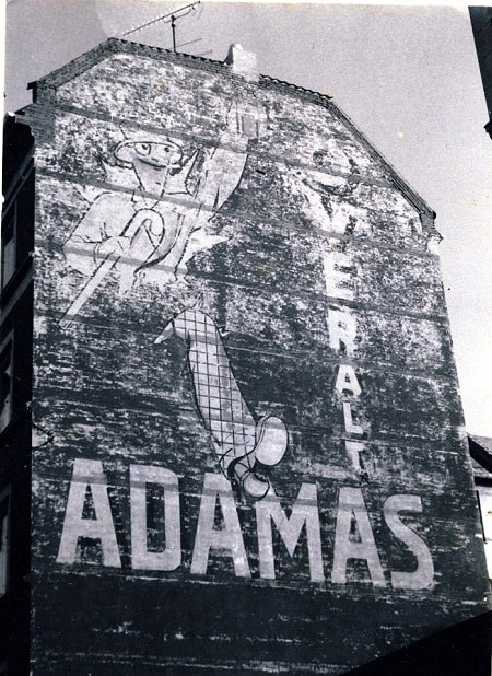 Fading painted advertisement on a wall promoting Adamas Cigarettes