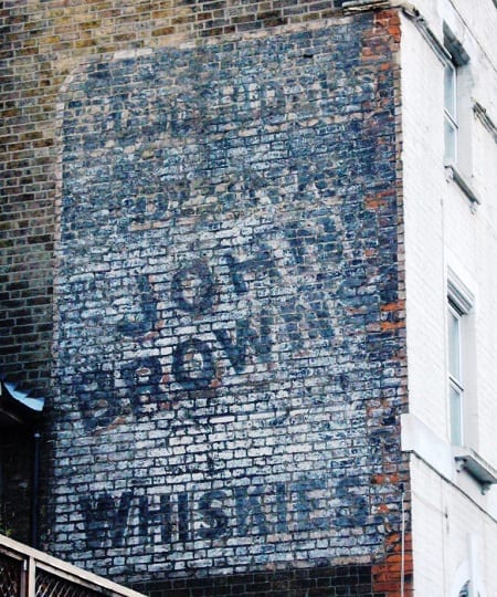 Fading sign painted on a wall advertising John Brown Whiskies