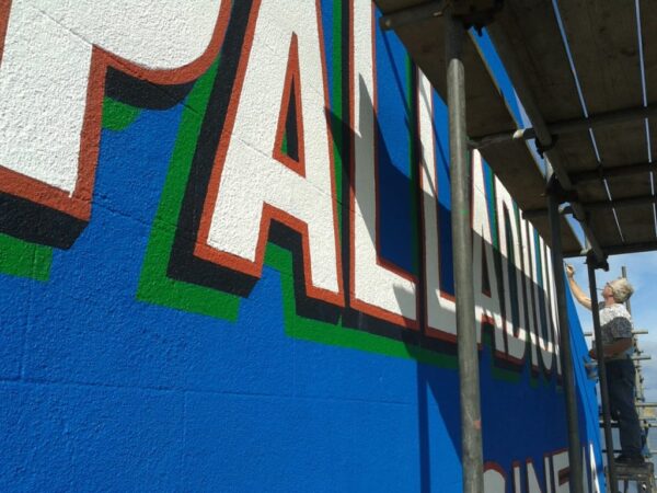 Work in progress on repainting a wall sign for the Palladium Cinema