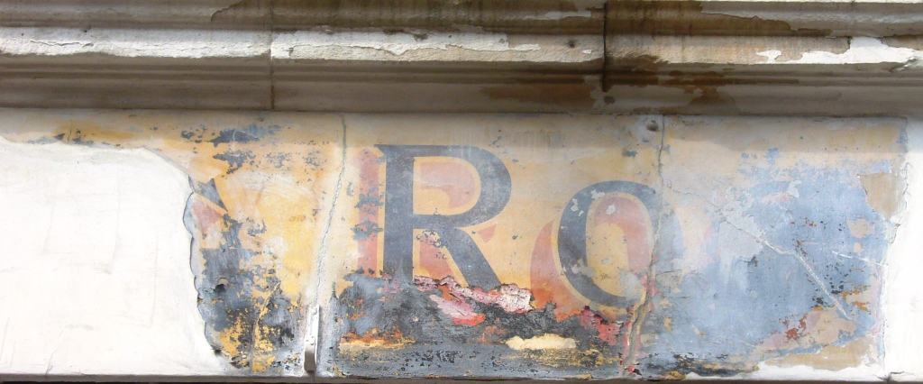Fading sign on wall with letters RO visible