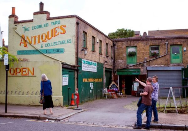 Two people looking at a painted sign on a wall for an antiques business