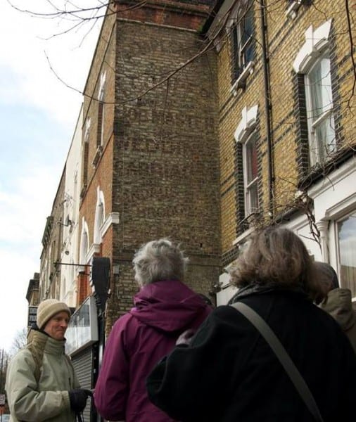 Tour group looking at a fading advertisement painted on a wall