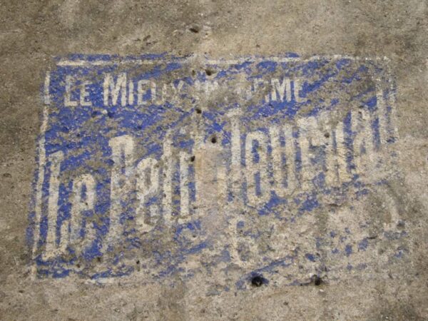 Painted sign fading on a wall advertising Le Petit Journal
