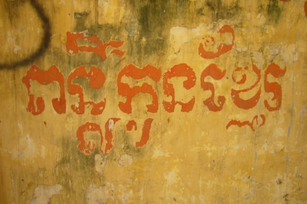 Fading khmer lettering on a wall saying Shining Future of Khmer Children