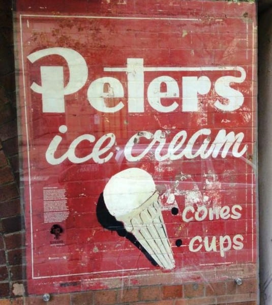 Painted sign on a wall covered by a perspex sheet