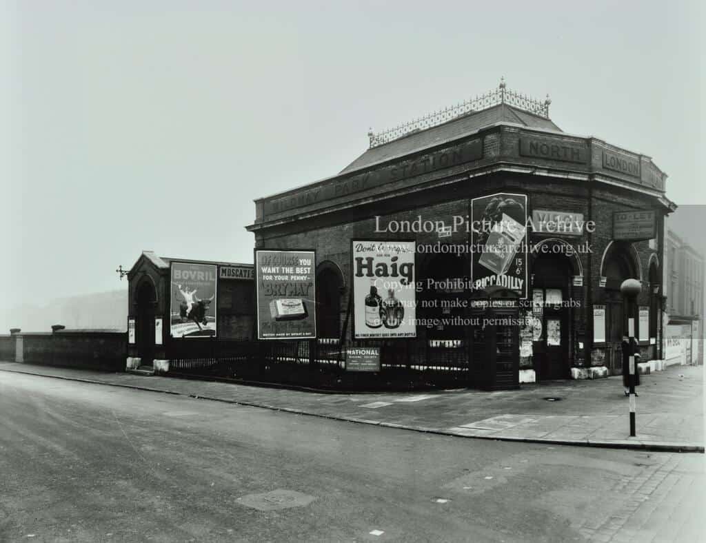 Advertisements outside station, including one for Haig whisky showing two bottles