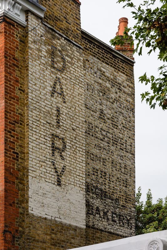 Fading painted signs advertising a dairy and the bakery of A.E. Cresswell.