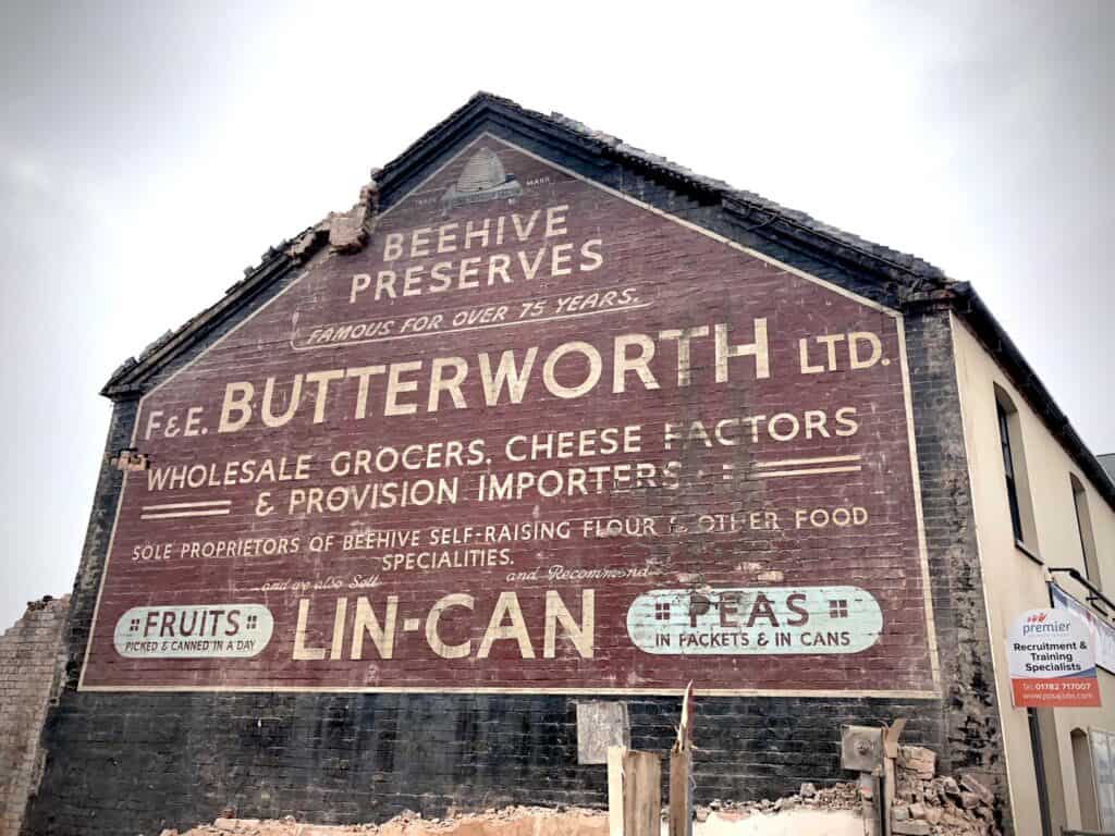 Painted wall sign on gable end of terrace advertising Beehive Preserves, F. & E. Butterworth and Lin-Can.
