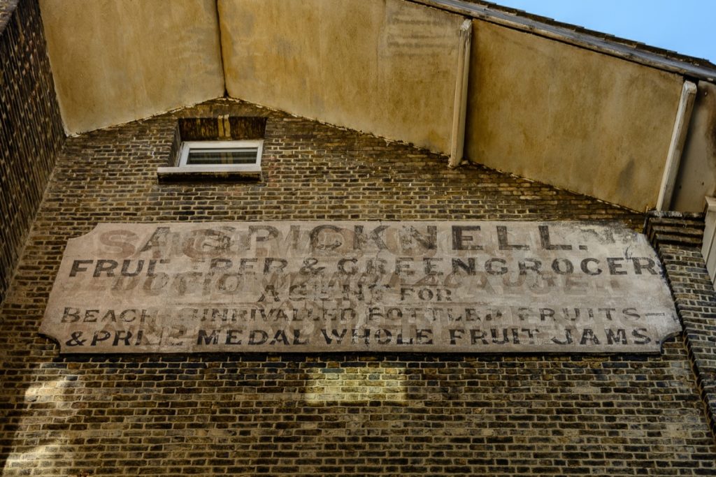 Layers of late-Victorian signwriting on a special render applied to a wall.